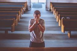 Mann betet in Kirche