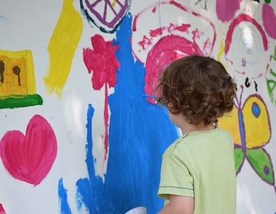 Junge malt mit Farben an die Wand